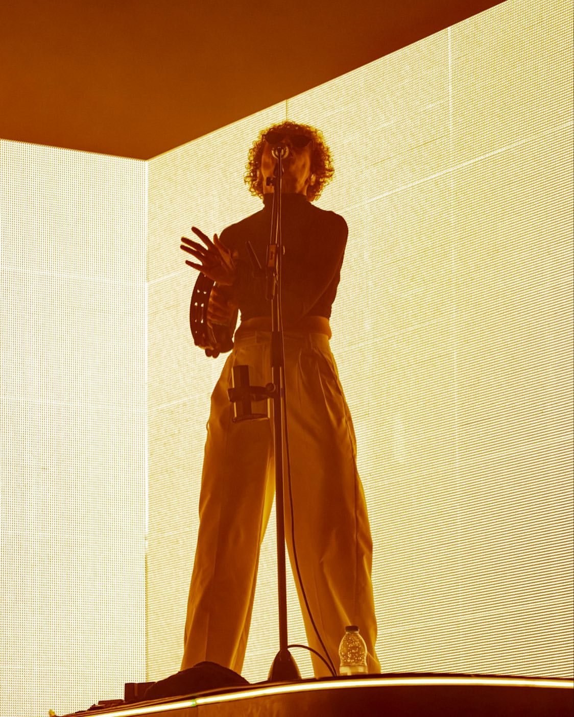 A performer silhouetted by pale vertical stage lights.