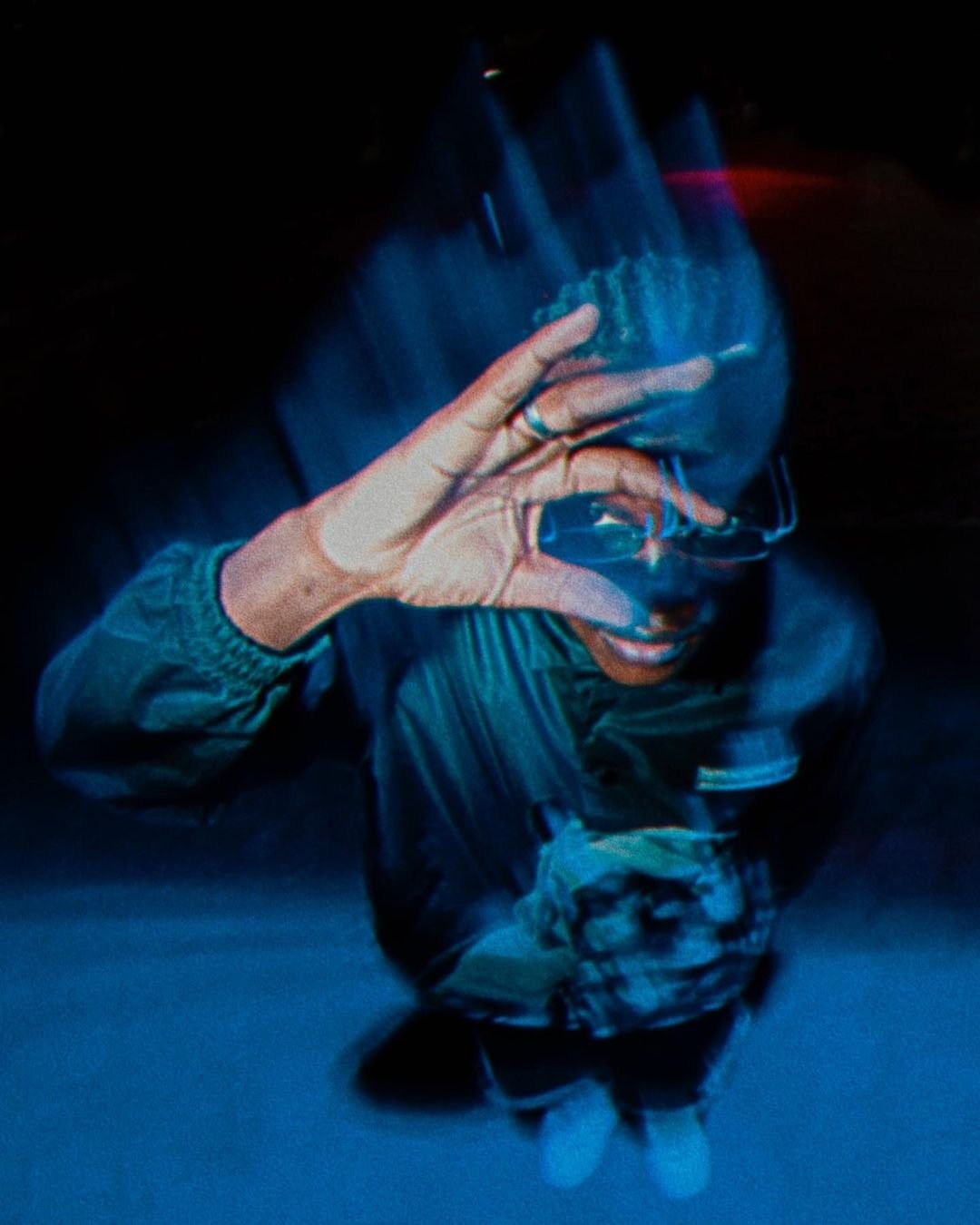 An inverted portrait with a raised hand and blue motion trails.