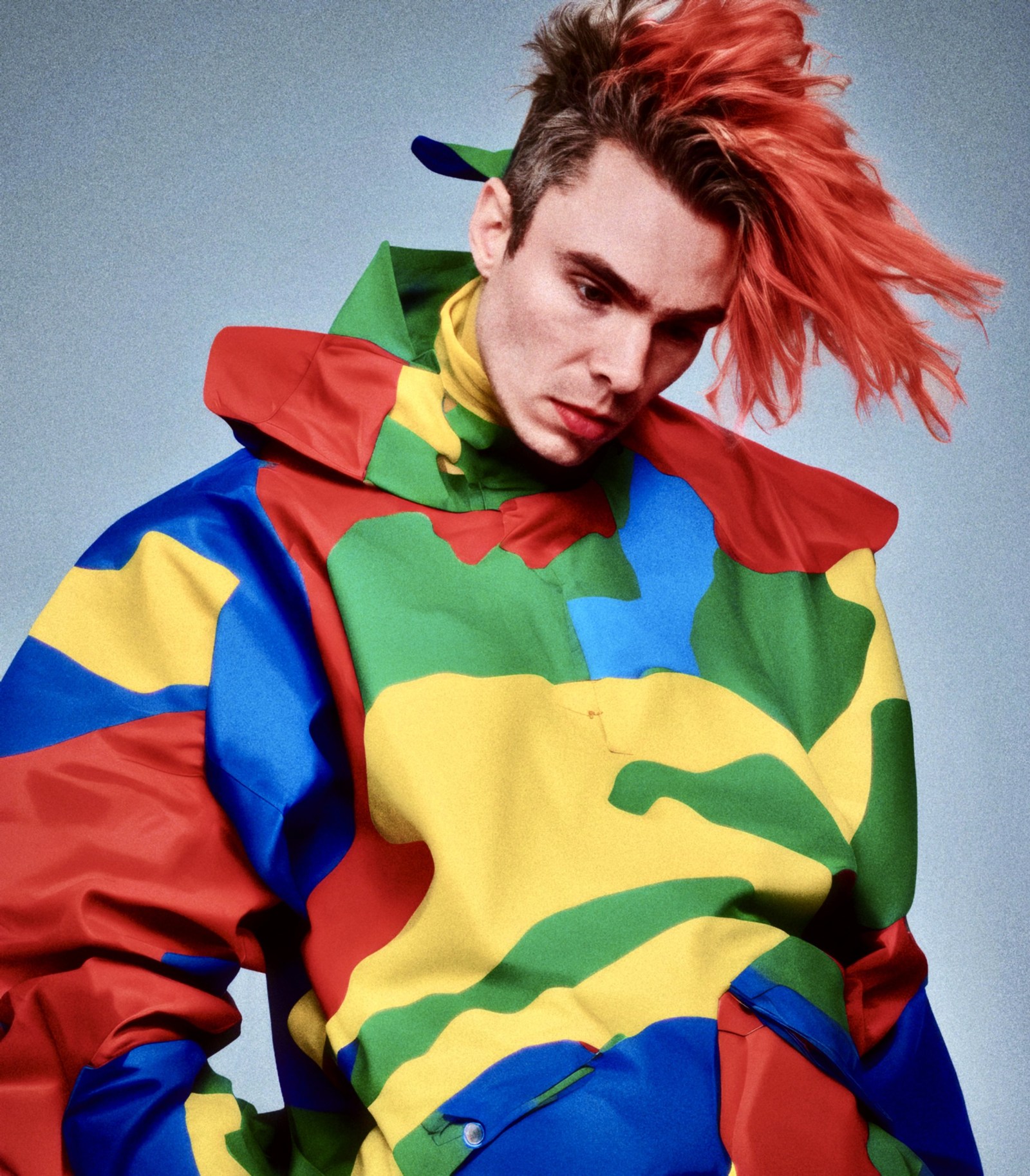 WORM in an oversized hooded top with broad green, yellow, blue and red shapes.