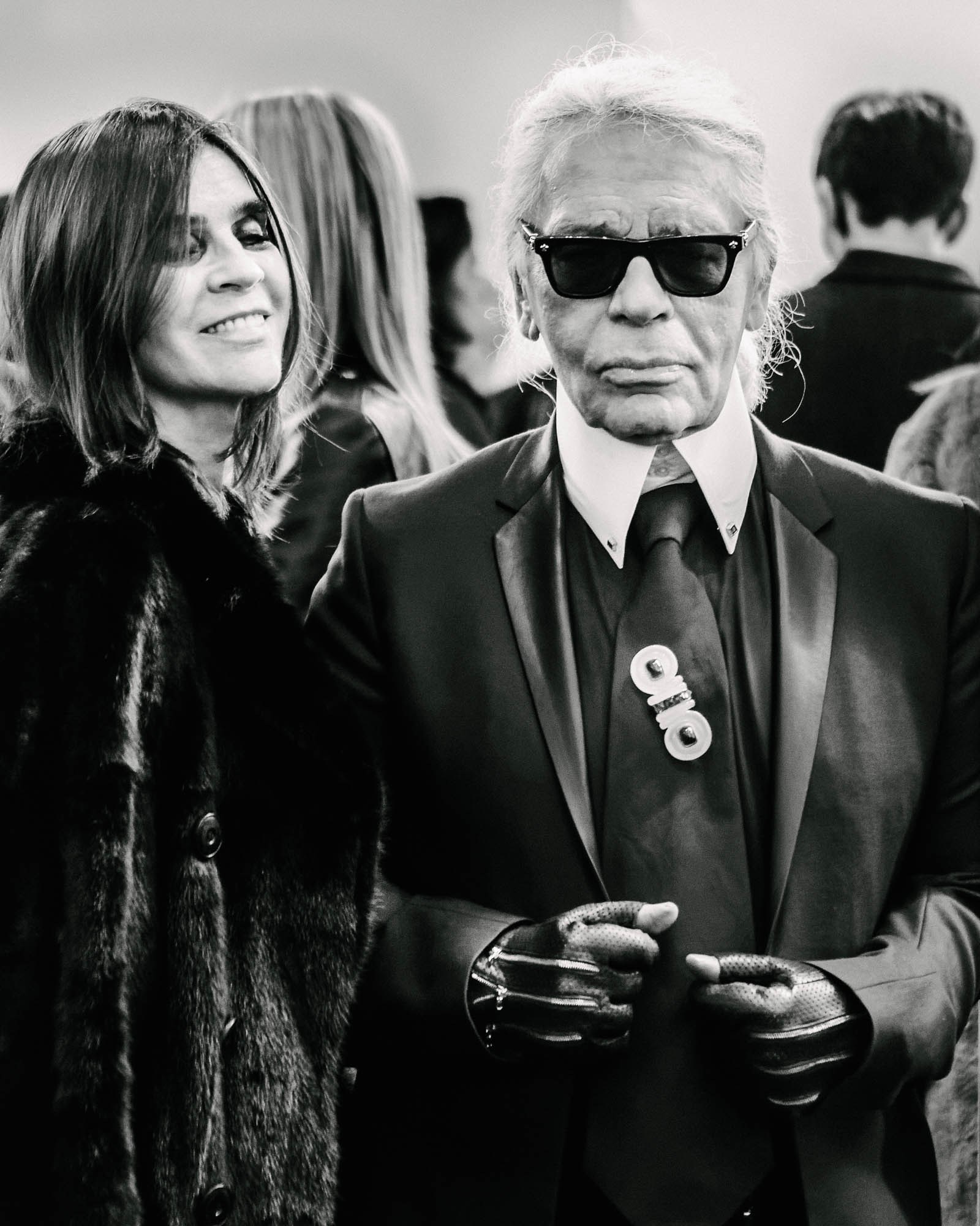 Black-and-white event photograph of two people, one wearing sunglasses and a dark suit.
