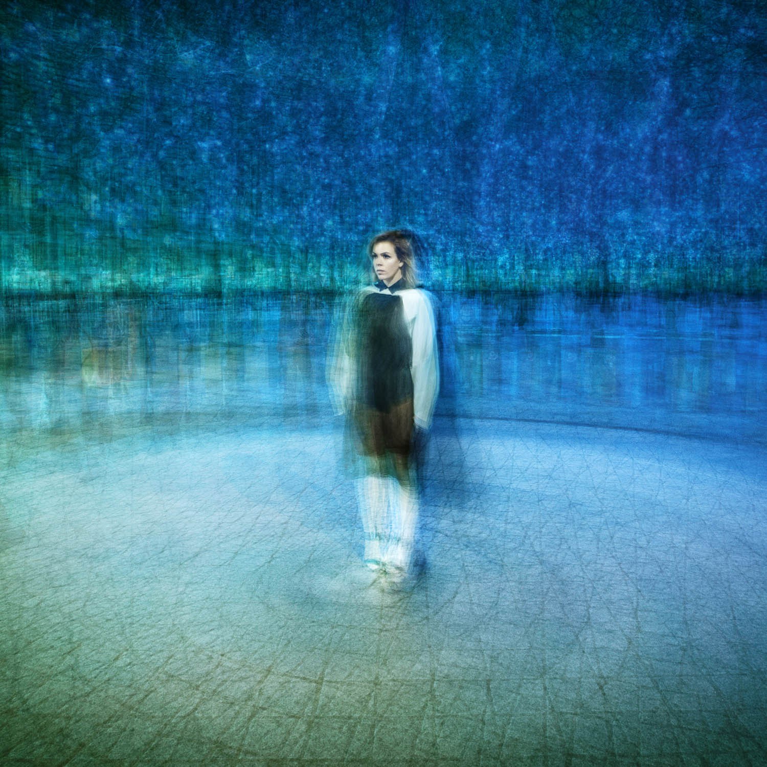 A solitary figure standing in a reflective blue-lit space.
