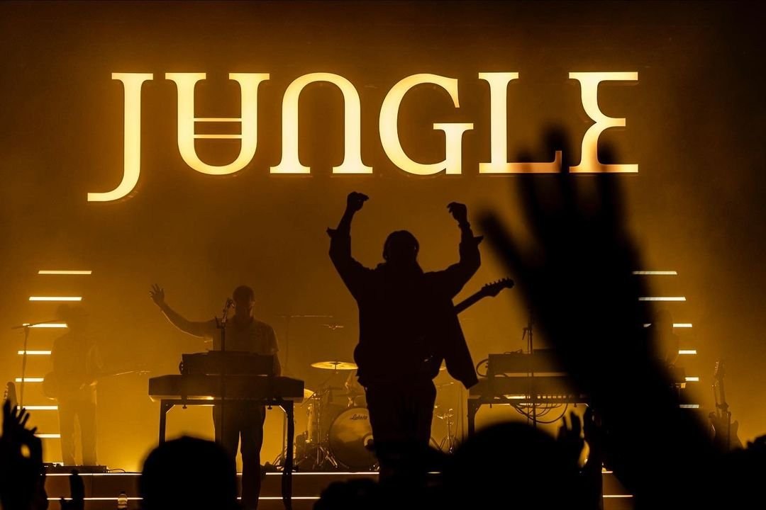 A concert stage with silhouetted musicians beneath large JUNGLE lettering.