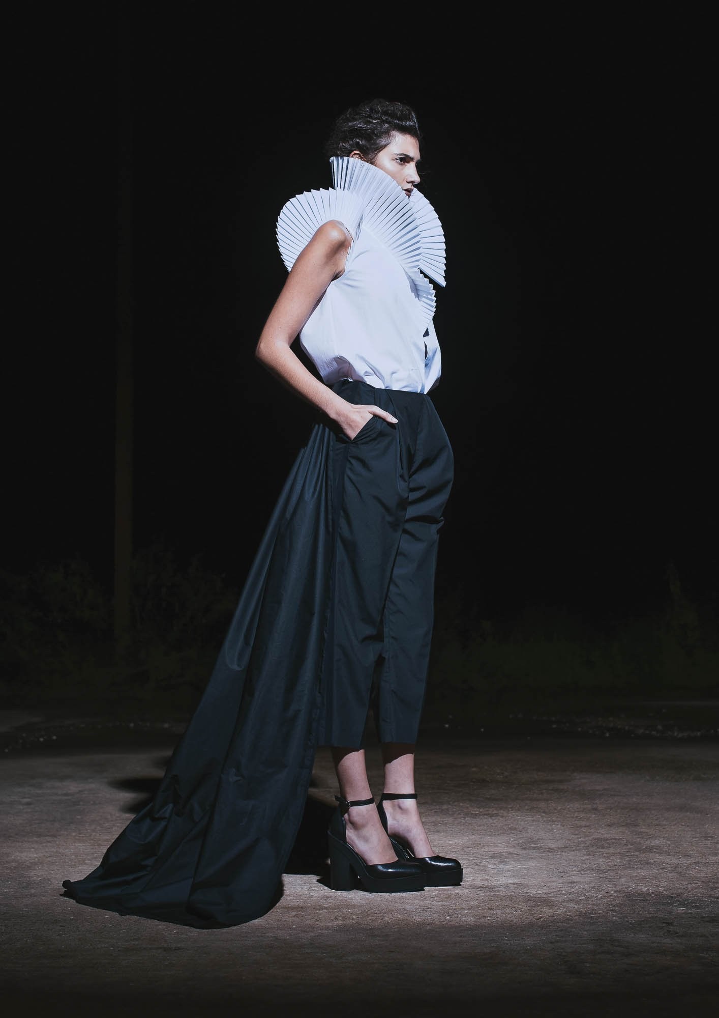 A runway model wearing a white sleeveless top and a long black skirt.