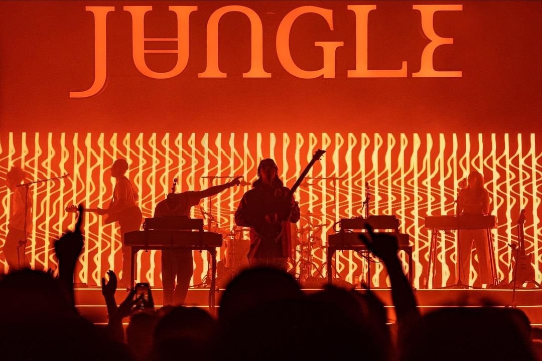 A concert audience beneath a stage glowing red, with JUNGLE lettering overhead.