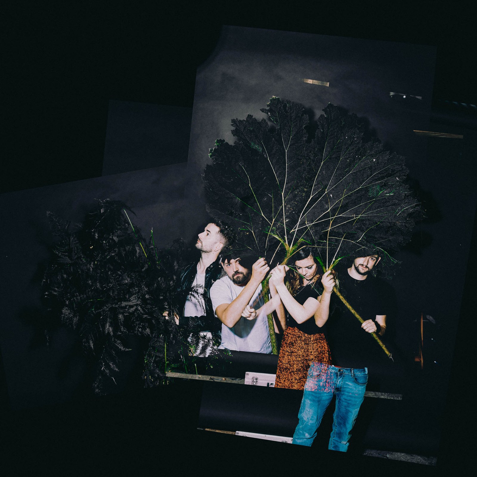 A small group gathered beside a piano against a dark wooded backdrop.