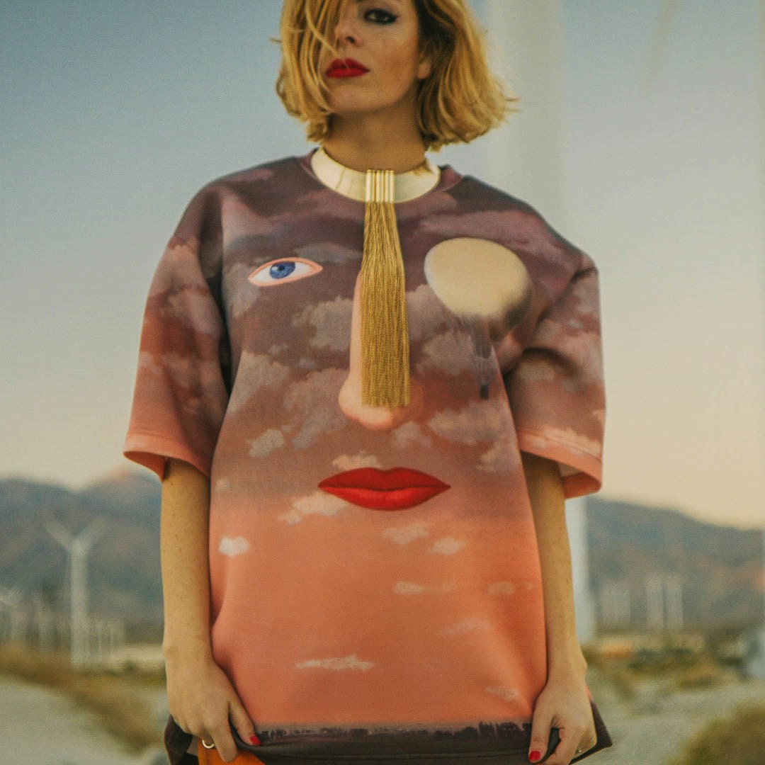A model wearing a translucent peach top printed with an oversized face.