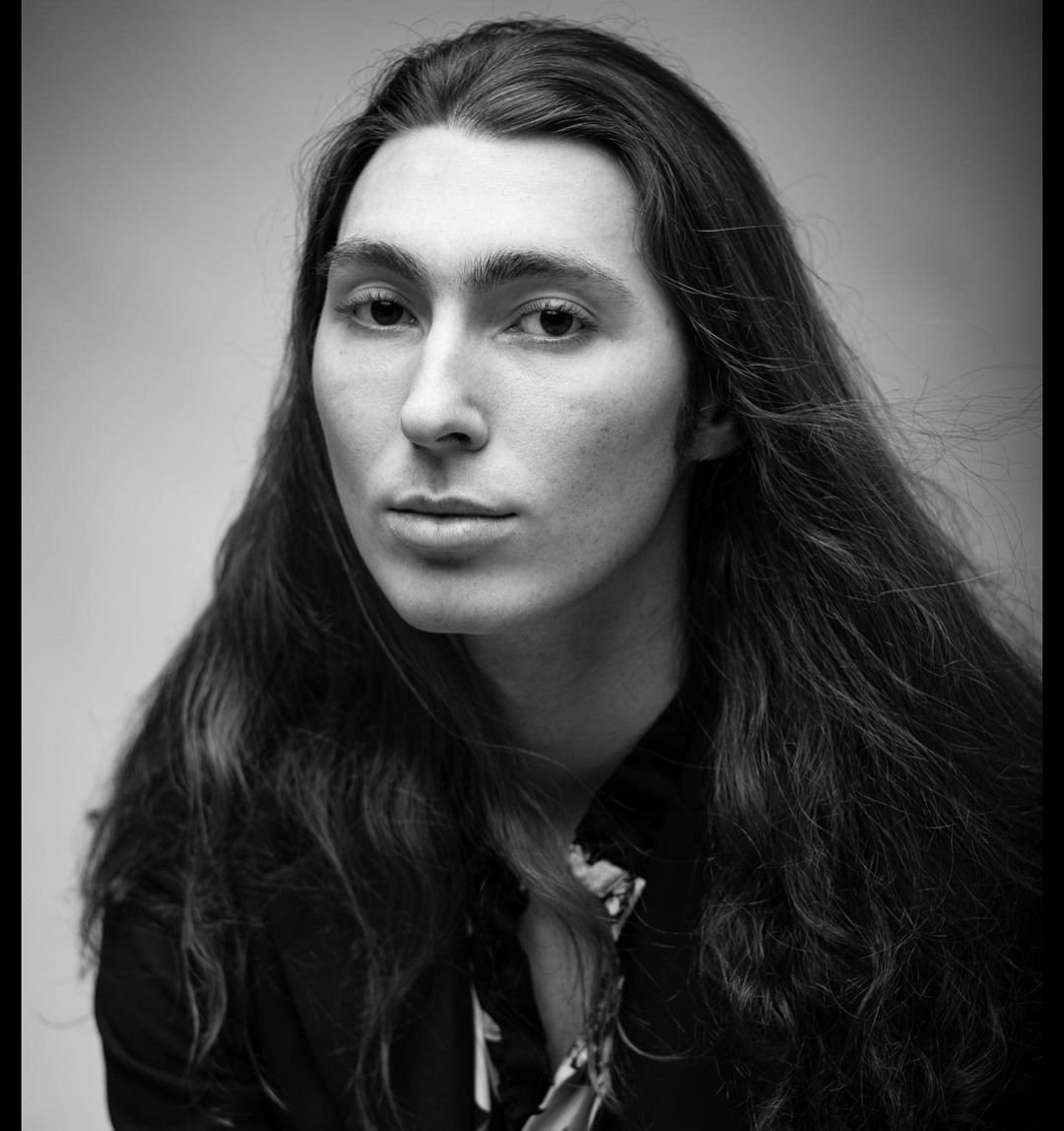 Black-and-white close portrait of a person with long dark hair.