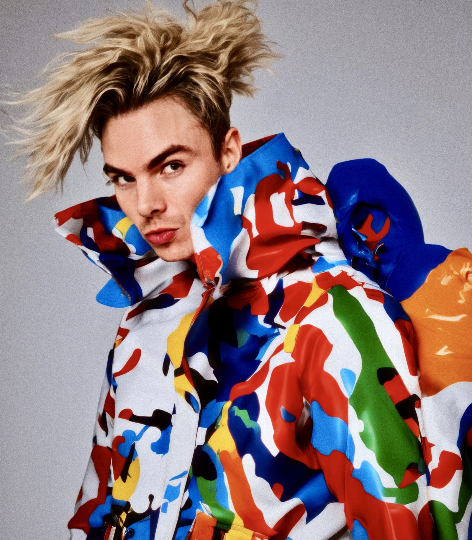 WORM portrait in a high-collared jacket covered with vivid red, blue, orange and green shapes.
