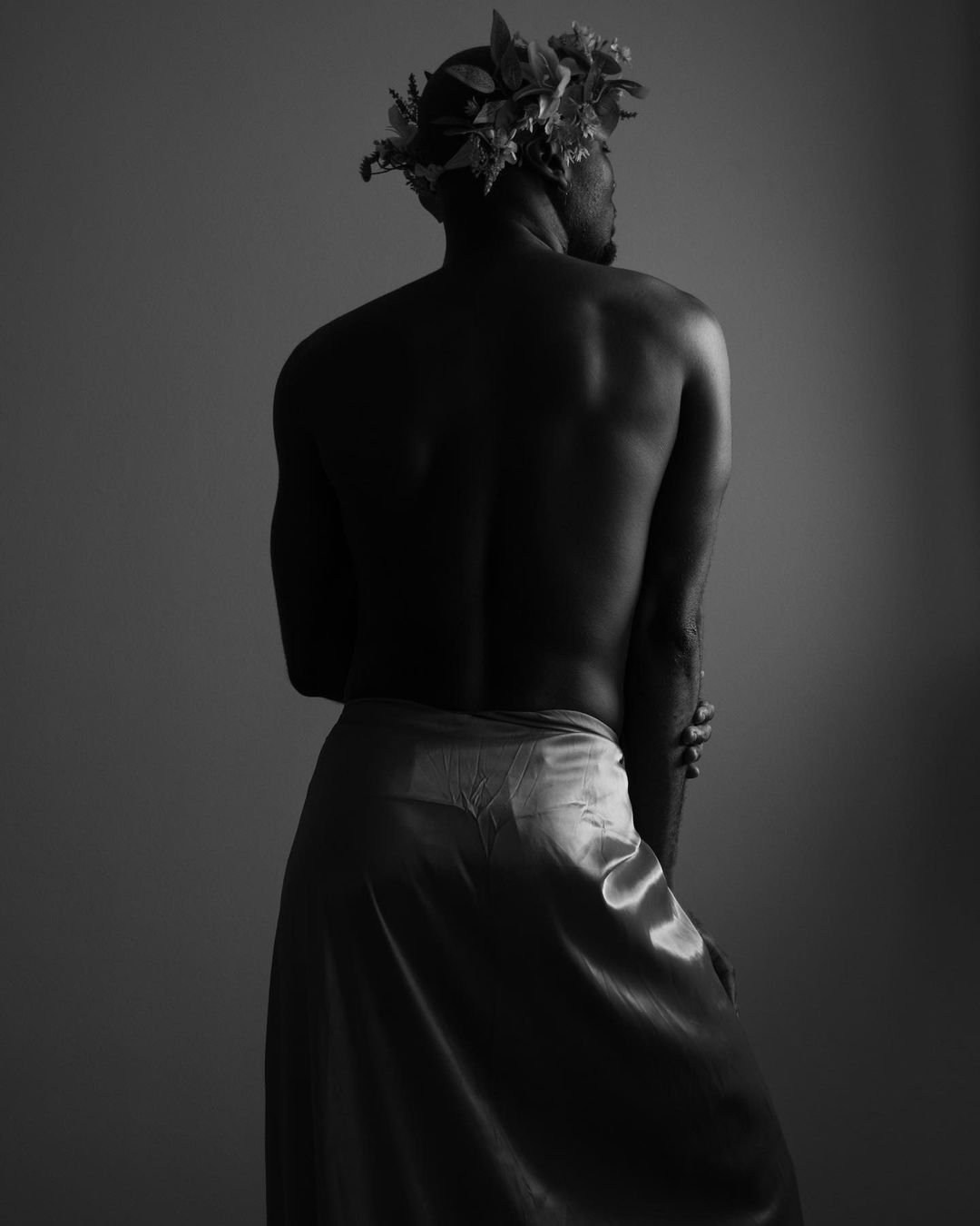 Black-and-white portrait of a bare-backed model with a high twisted hairstyle.