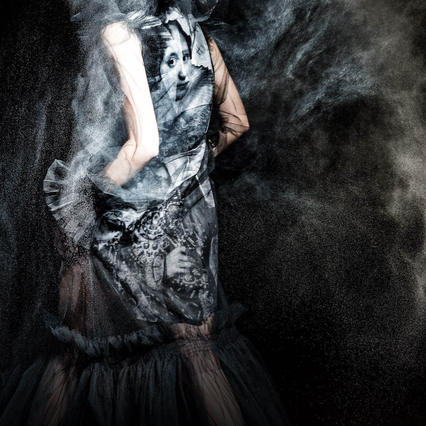 A dark, textured fashion portrait of a model in a sculptural dress amid smoke.