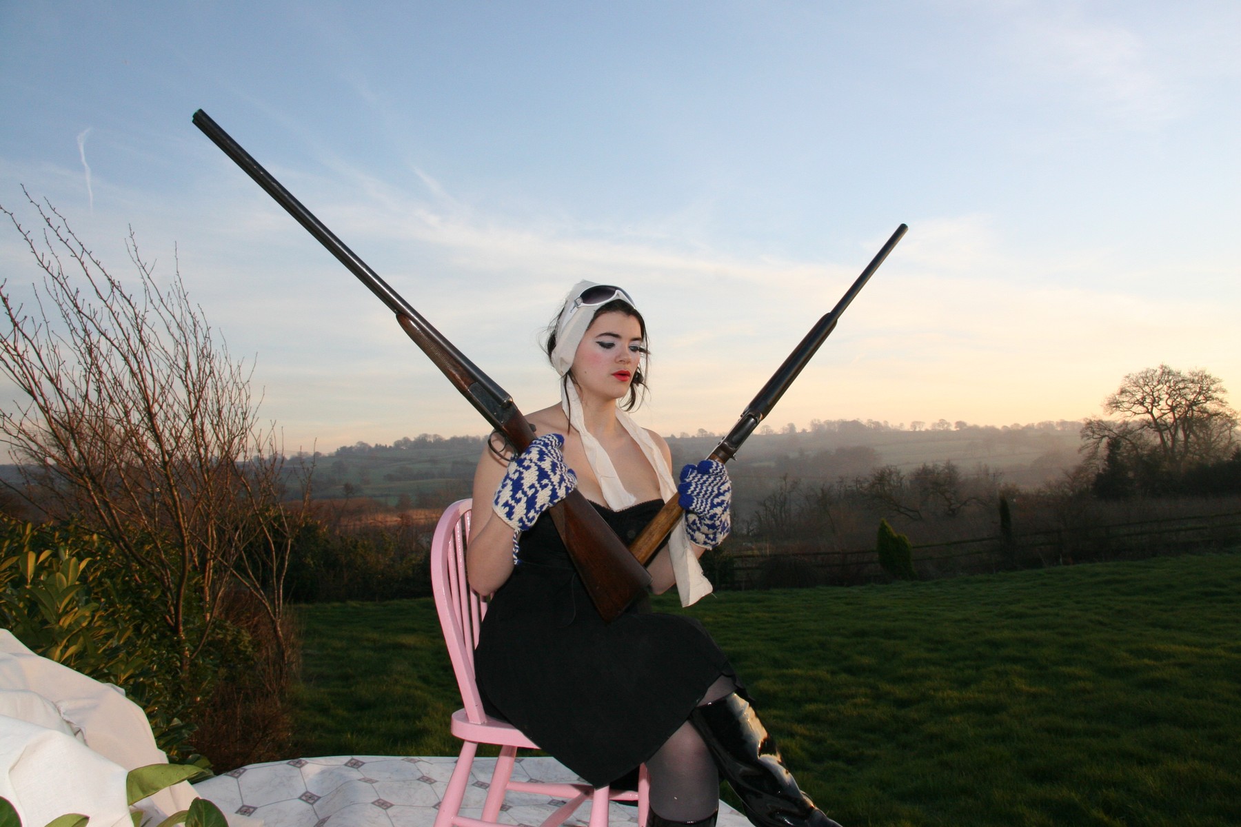 A seated figure holding an open gun against the evening sky.