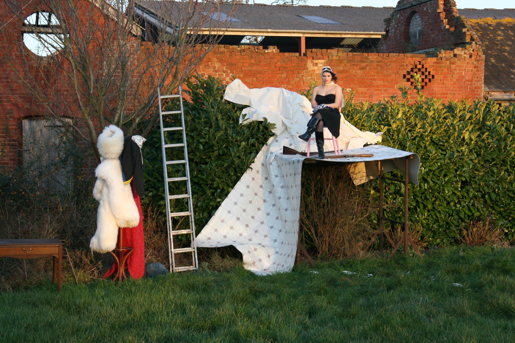The complete garden set: raised stage, draped fabric, dress forms and a weathered brick wall.