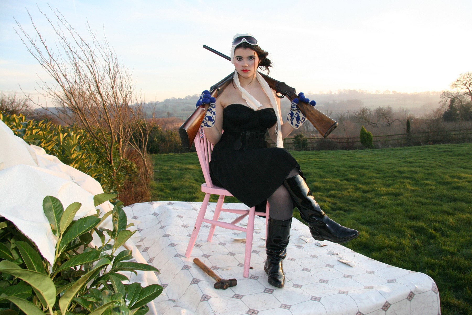 A wide seated portrait on the pink chair with green fields behind the patterned stage.