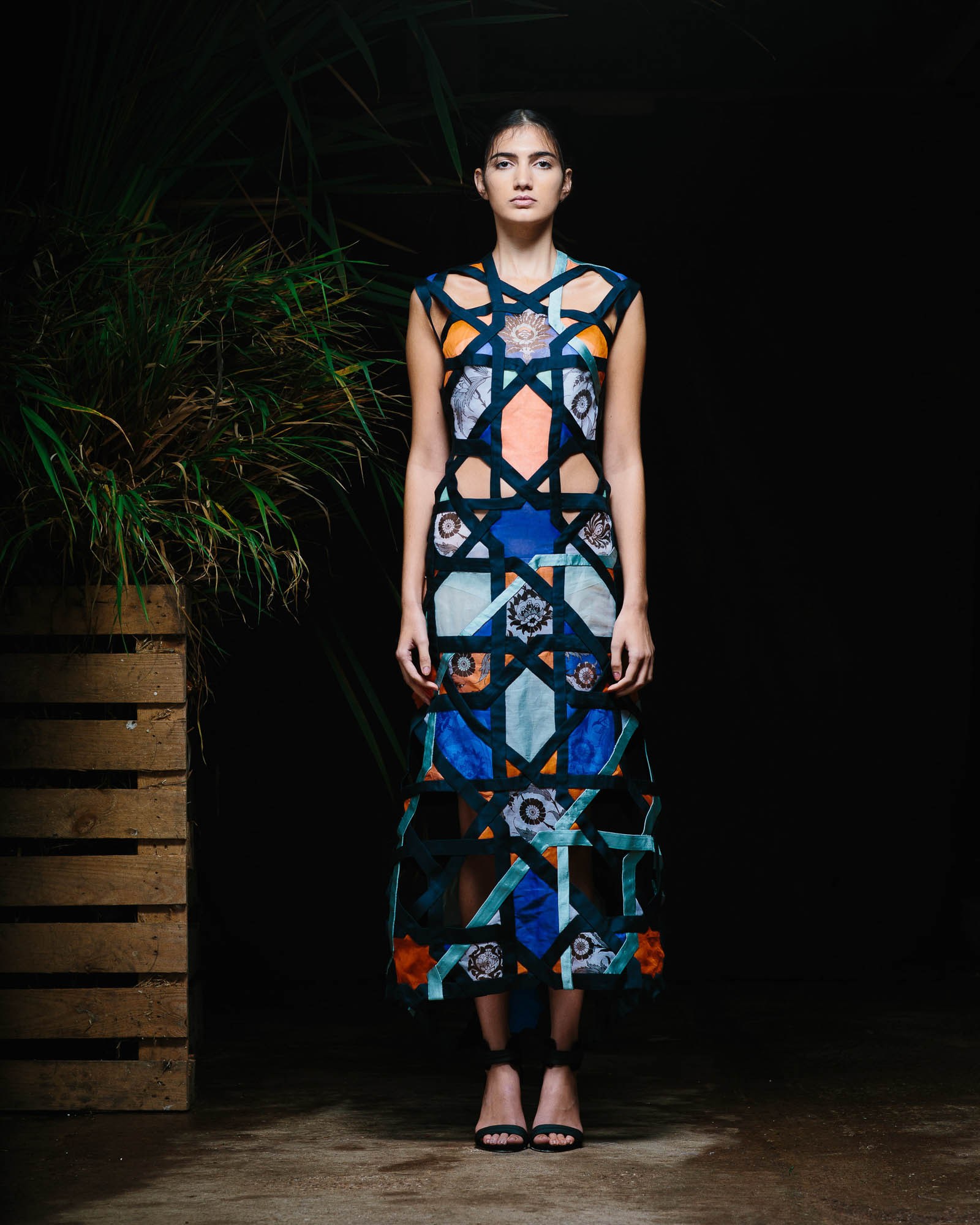 A runway model wearing a sleeveless dress with bold blue and orange patterns.