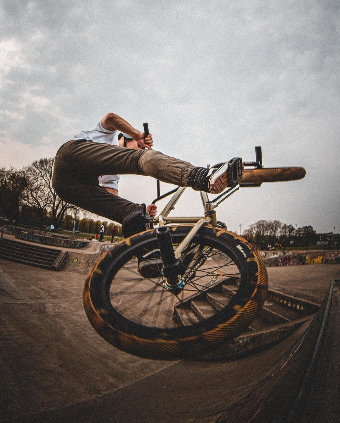 A BMX rider balancing above a ramp beneath a cloudy sky.