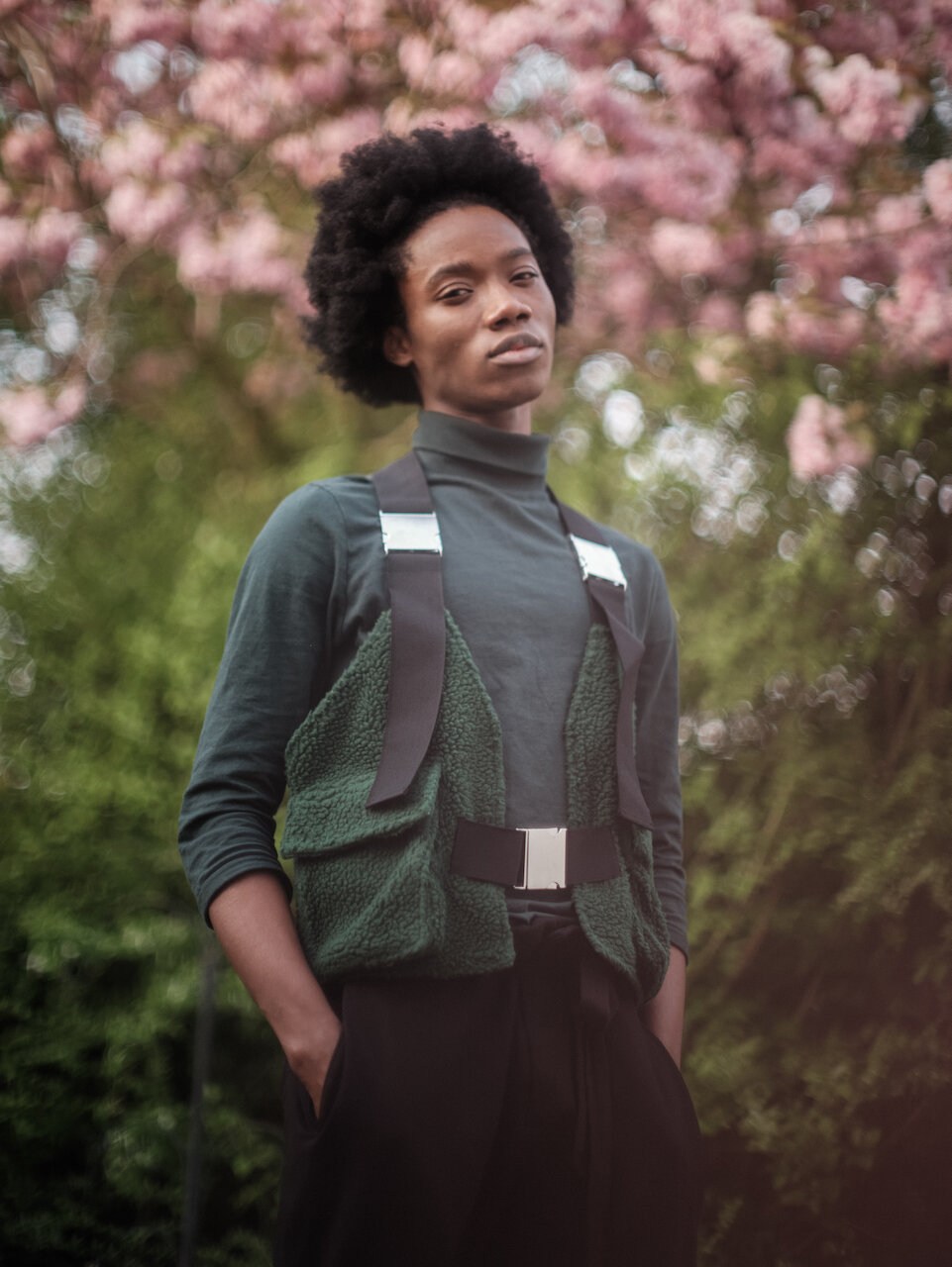 A model in a dark waistcoat beneath pink blossom.