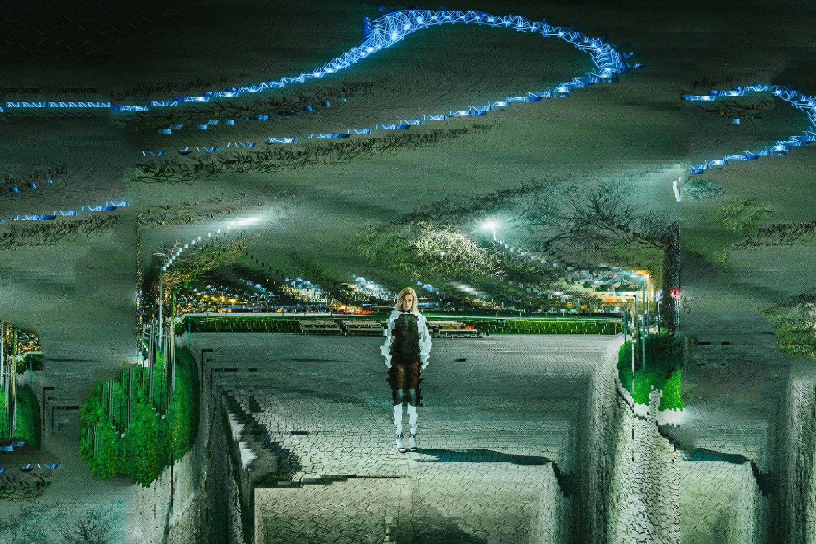 A lone figure inside a reflective installation with curved metallic forms and blue light.