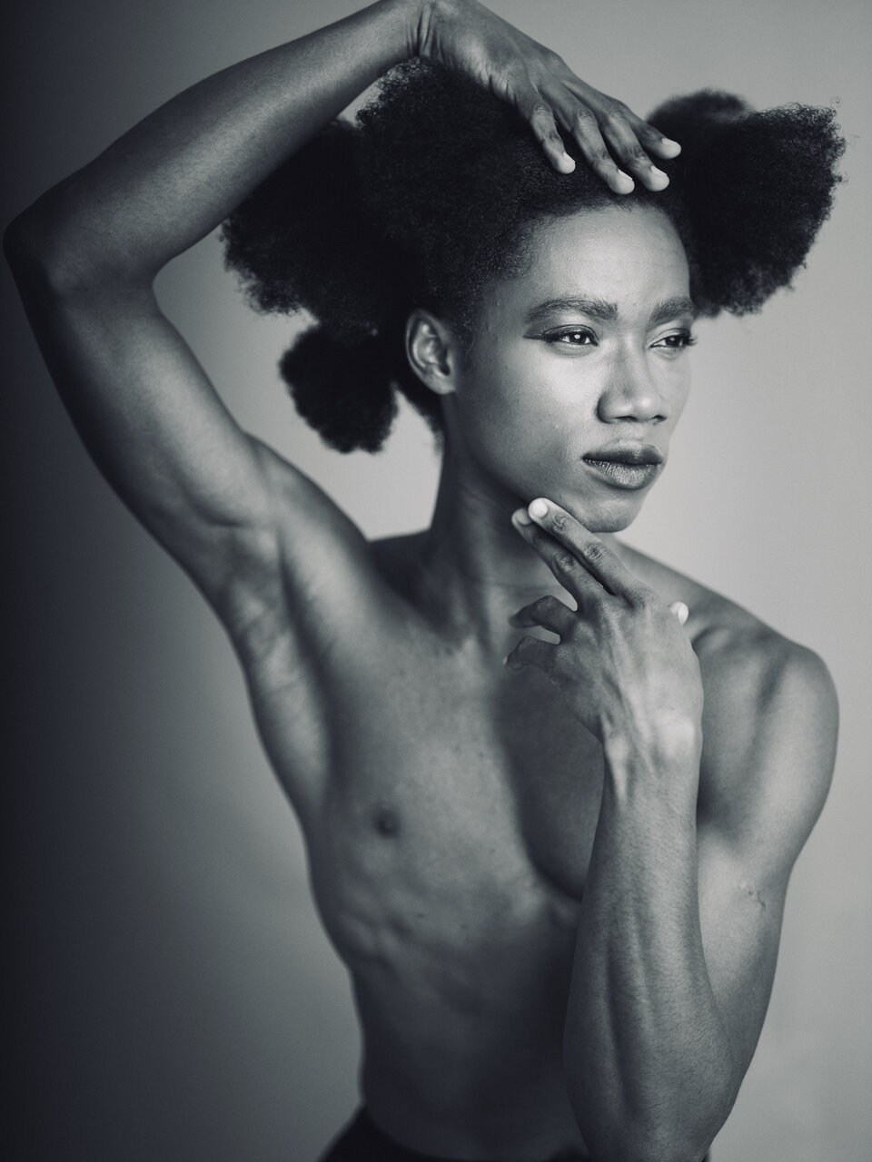 Black-and-white portrait of a model with one arm raised above their head.